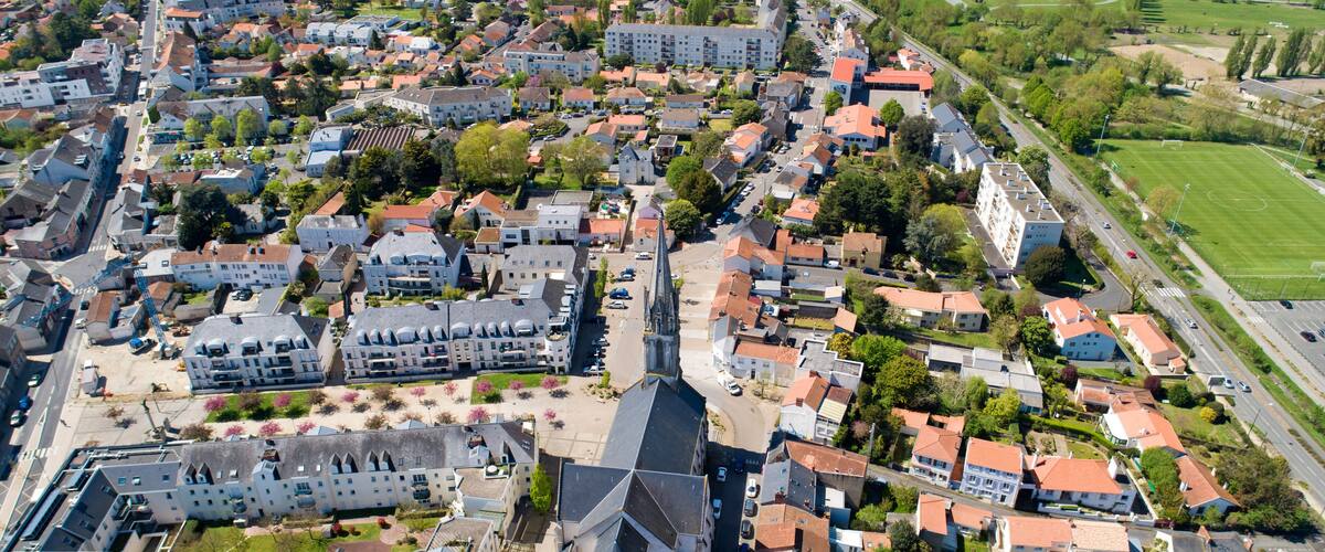 An aerial view of a town with a prominent church, residential buildings, and a sports field.