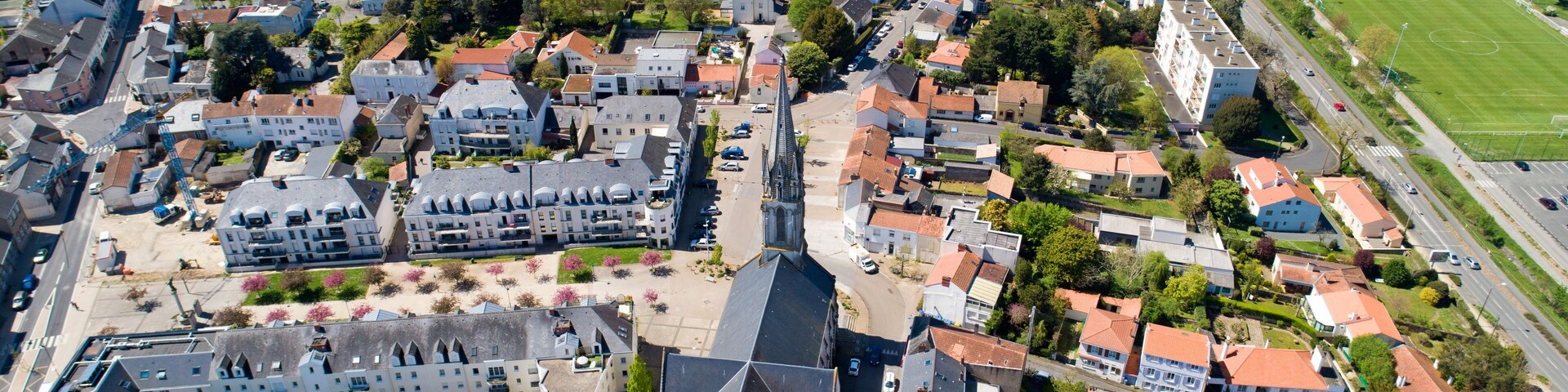 An aerial view of a town with a prominent church, residential buildings, and a sports field.