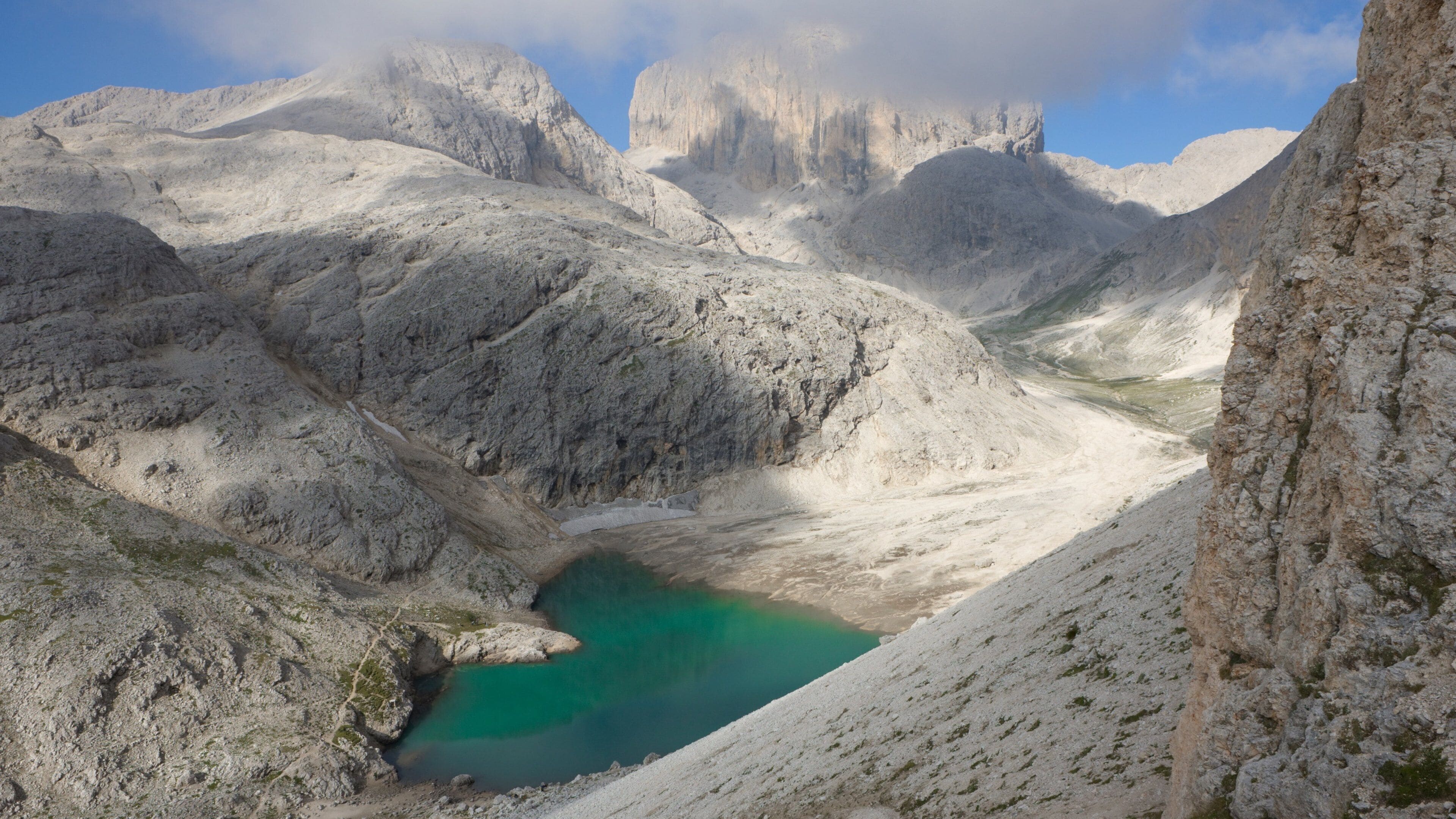 A mountainous landscape with a turquoise lake surrounded by rocky terrain and towering peaks.