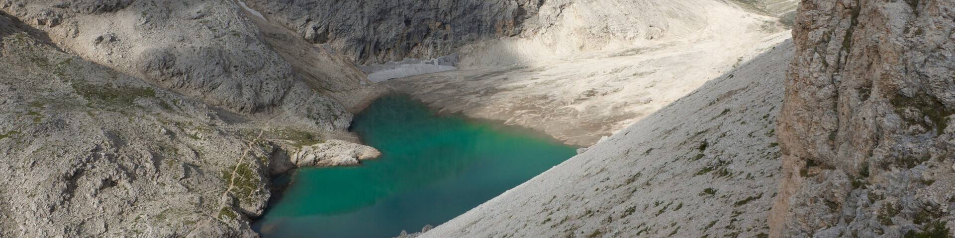 A mountainous landscape with a turquoise lake surrounded by rocky terrain and towering peaks.