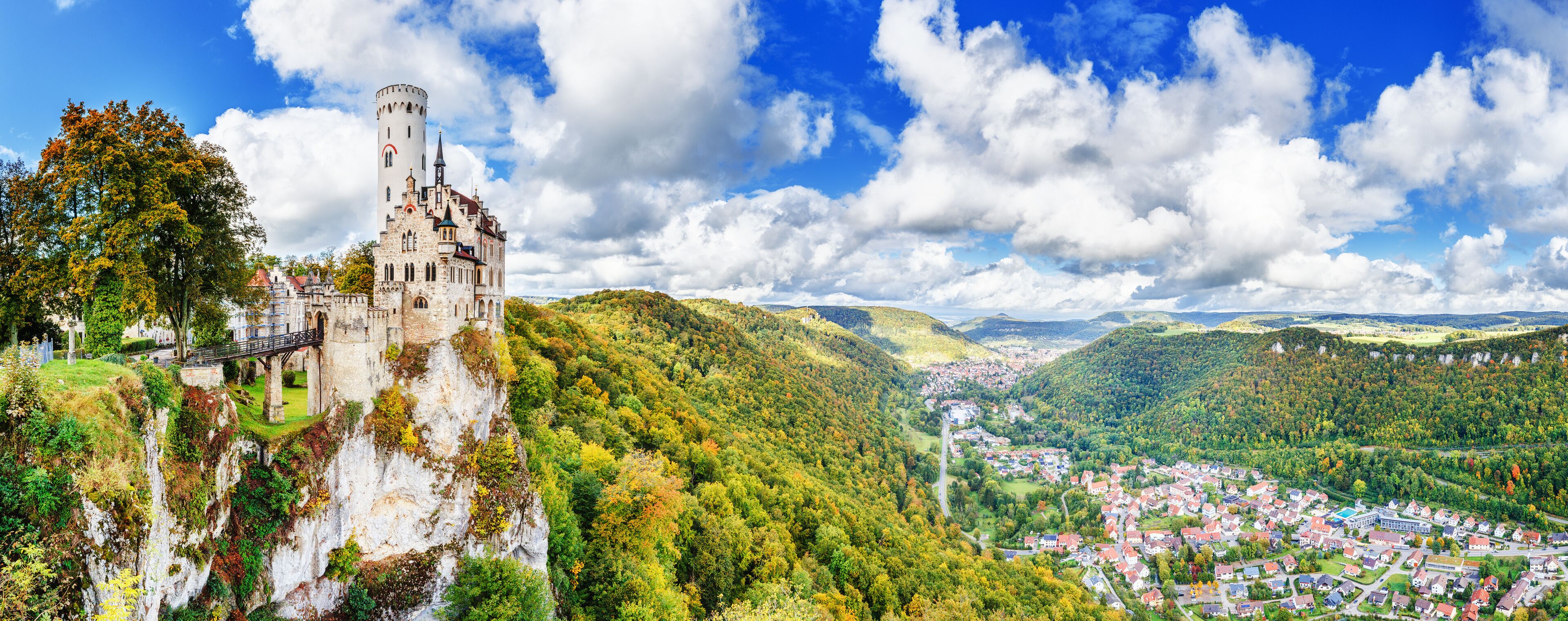 Germany, Lichtenstein Castle in Baden-Wurttemberg land in Swabian Alps. Seasonal panorama of  Lichtenstein Castle on a cliff circled by colorful trees, German countryside . European famous landmark.