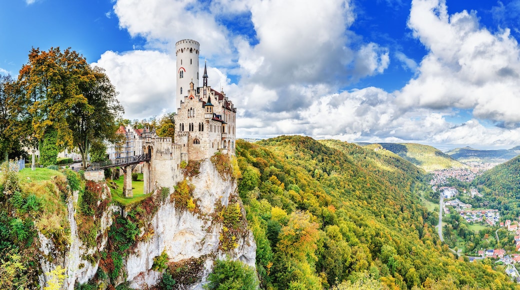 Germany, Lichtenstein Castle in Baden-Wurttemberg land in Swabian Alps. Seasonal panorama of Lichtenstein Castle on a cliff circled by colorful trees, German countryside . European famous landmark.