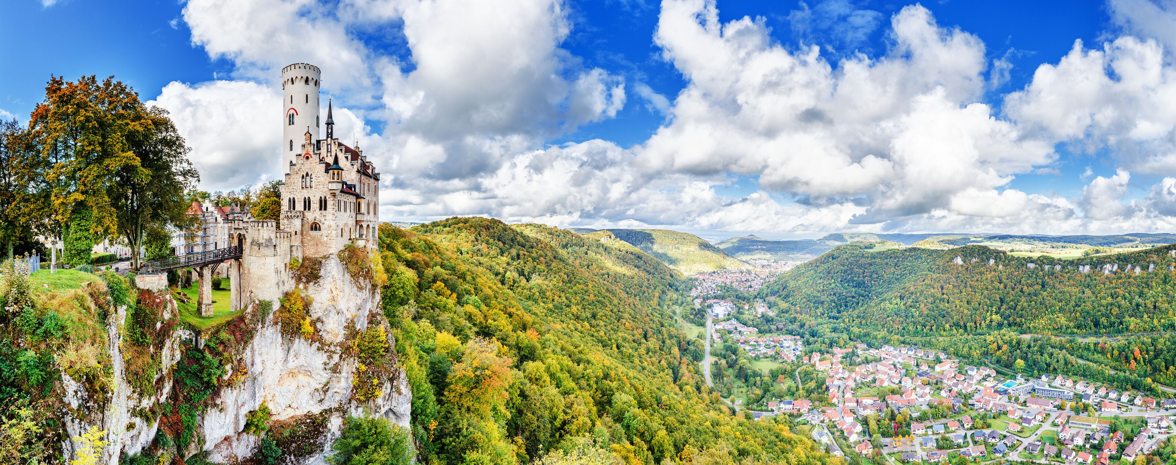 Germany, Lichtenstein Castle in Baden-Wurttemberg land in Swabian Alps. Seasonal panorama of  Lichtenstein Castle on a cliff circled by colorful trees, German countryside . European famous landmark.