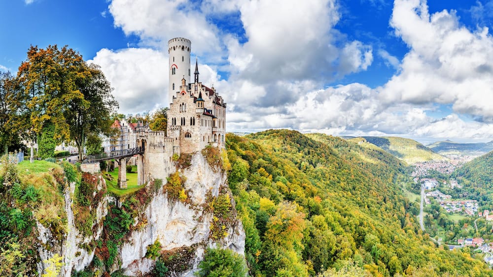 Germany, Lichtenstein Castle in Baden-Wurttemberg land in Swabian Alps. Seasonal panorama of Lichtenstein Castle on a cliff circled by colorful trees, German countryside . European famous landmark.