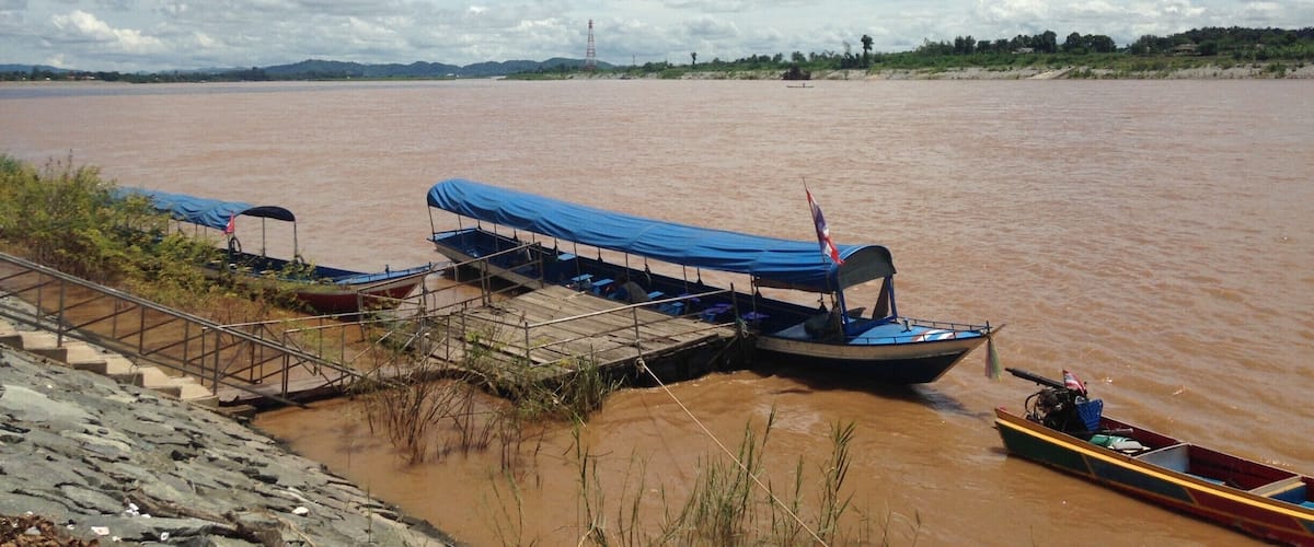 A river with boats docked at a wooden pier.