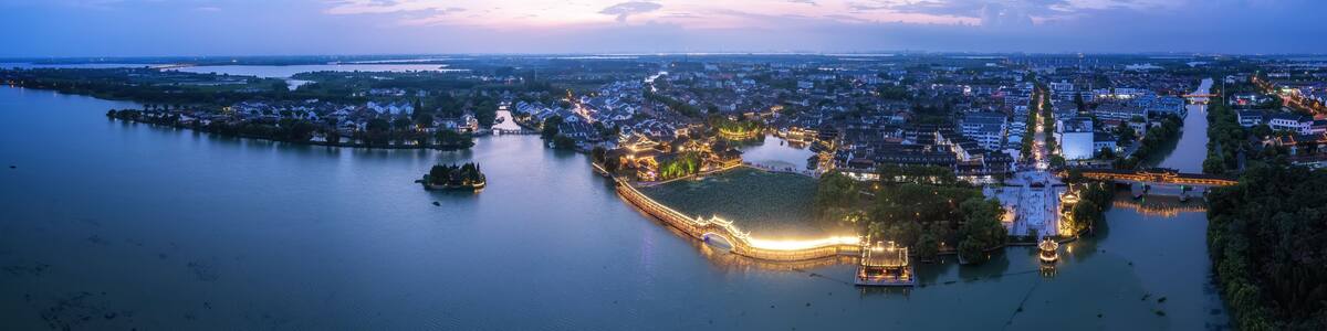 A river with a bridge and illuminated buildings at dusk.