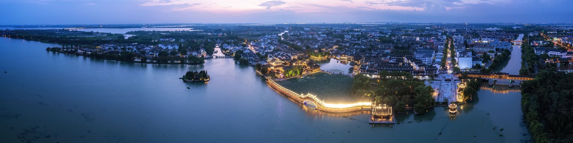 A river with a bridge and illuminated buildings at dusk.