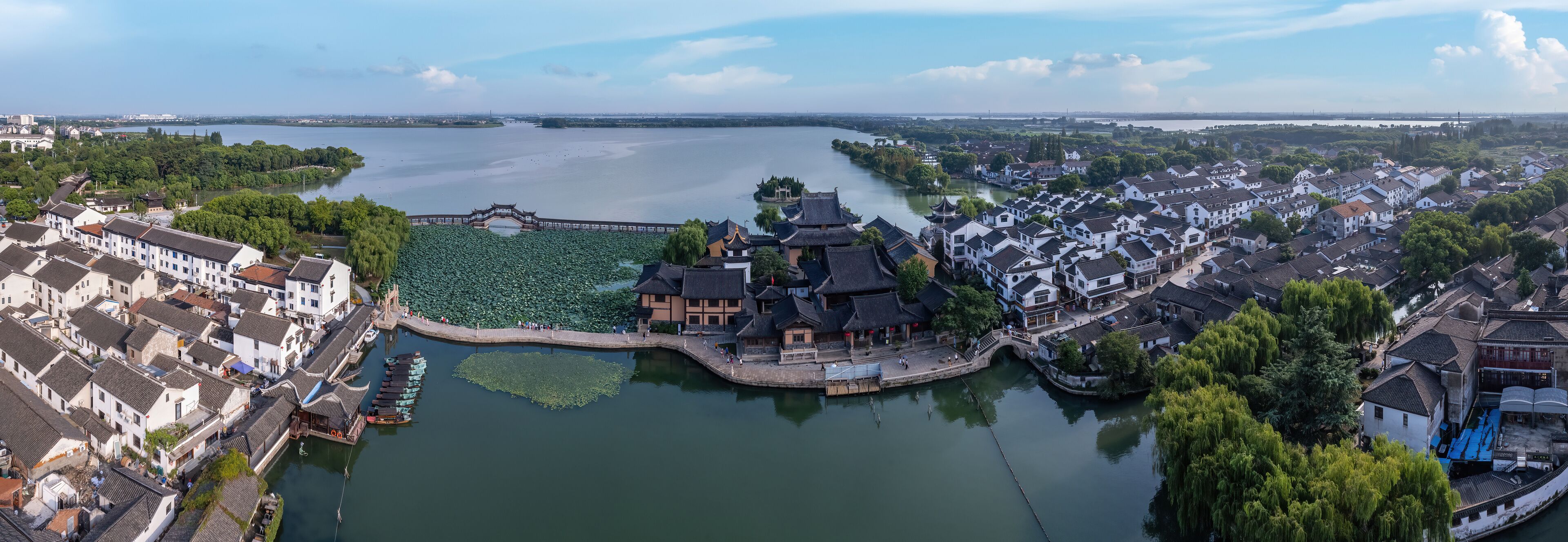 A riverside town with traditional architecture, a bridge, and a large body of water.