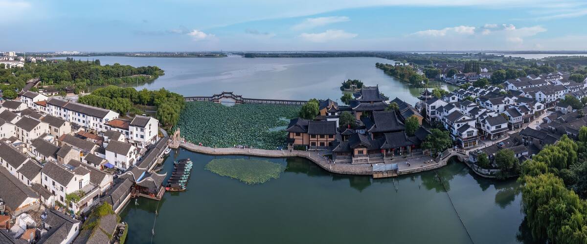 A riverside town with traditional architecture, a bridge, and a large body of water.