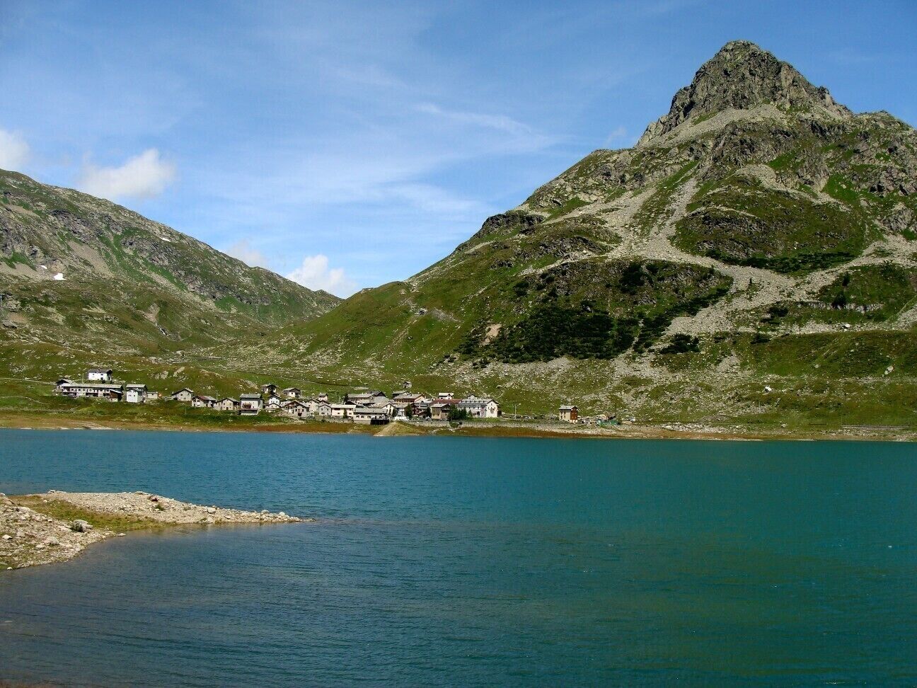 A lake with a mountain in the background and a small village with houses along the shore.