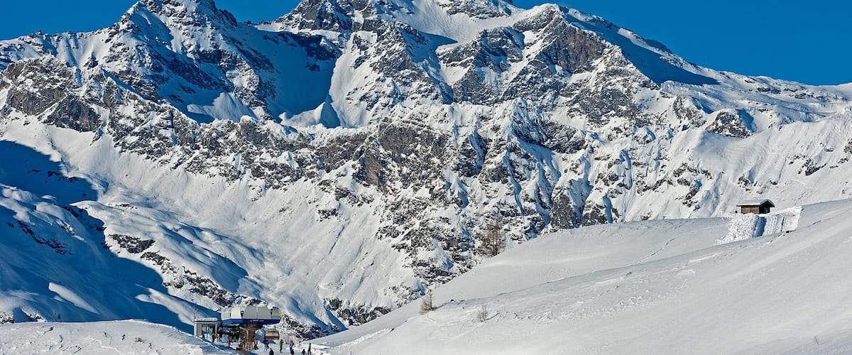 A snow-covered mountain with a ski resort and a small lodge.
