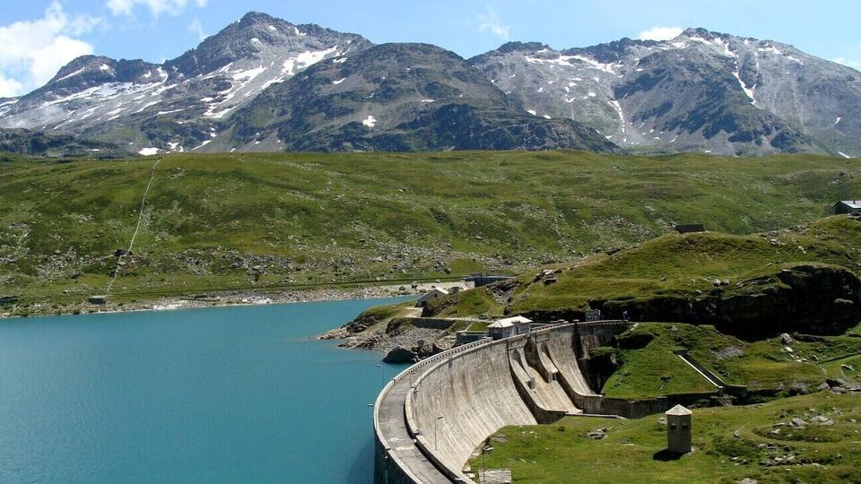 A dam with a reservoir and mountains in the background.