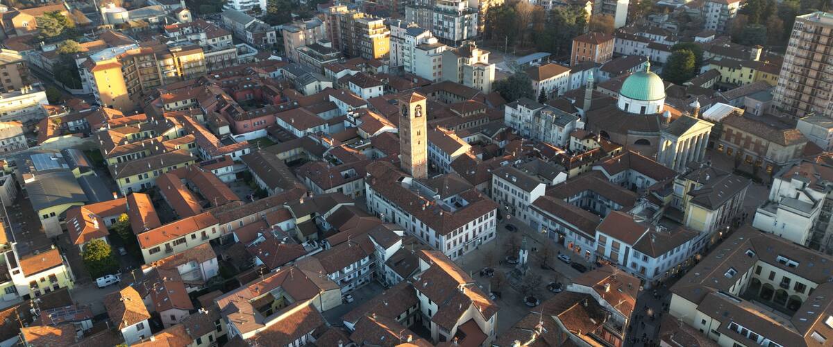 An aerial view of a densely packed urban area with historic buildings, narrow streets, and a prominent clock tower.