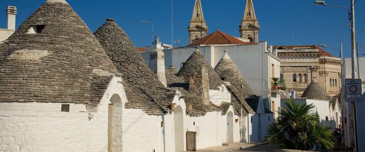 A street lined with traditional stone-roofed buildings and a church with two towers.