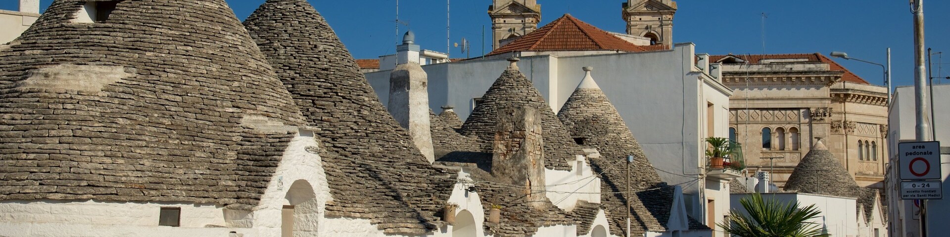 A street lined with traditional stone-roofed buildings and a church with two towers.