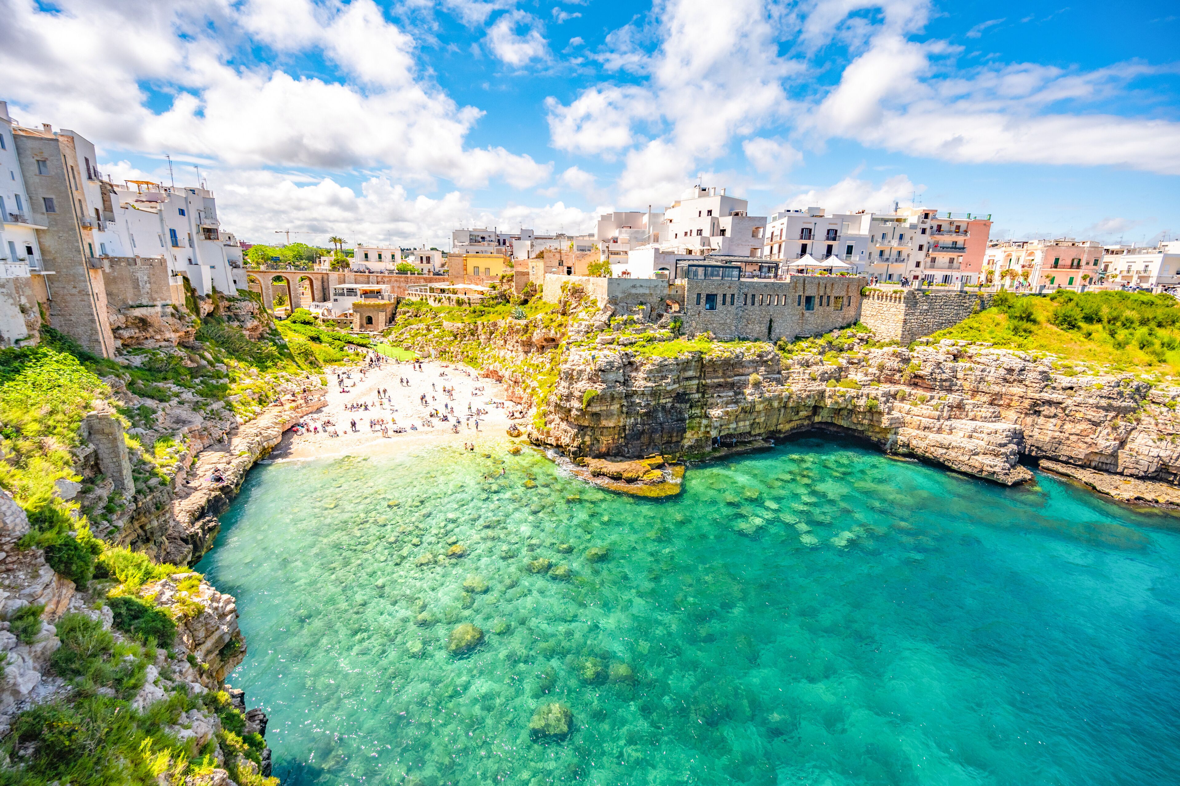 Un pueblo costero con un mar turquesa cristalino, acantilados rocosos y edificios blancos.