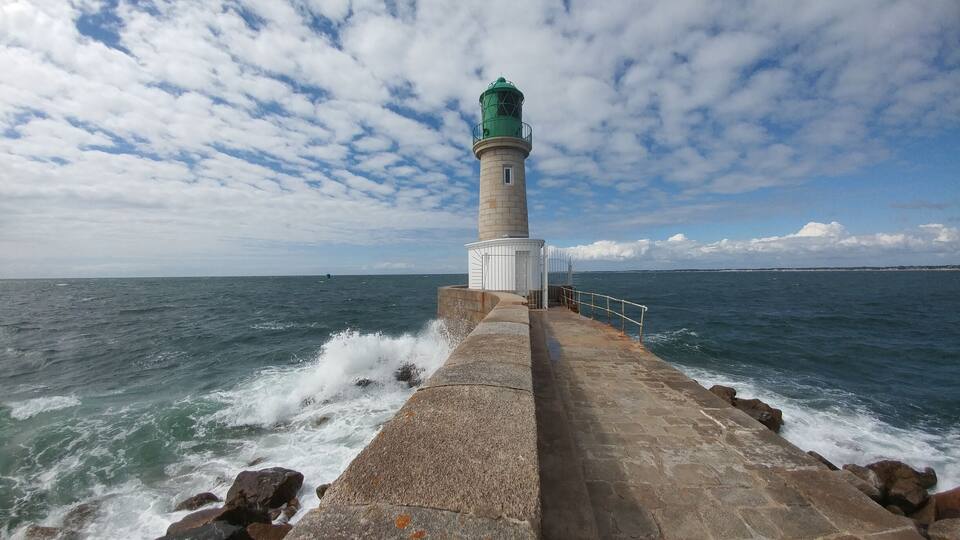 A lighthouse by the sea with waves crashing against the rocks.