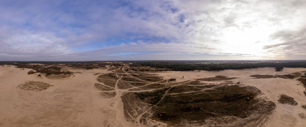 A vast desert landscape with winding roads and scattered vegetation.