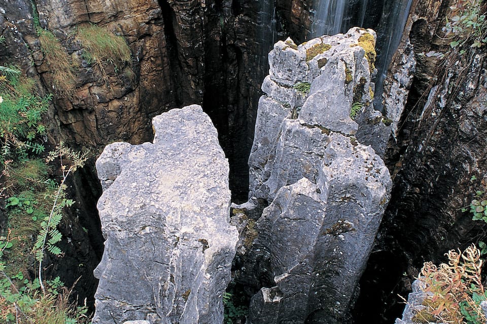 A waterfall cascading down a rocky cliff surrounded by large boulders.
