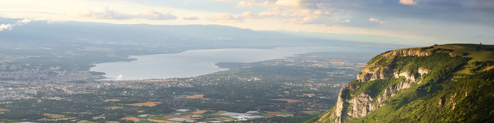 Un paisaje montañoso con un valle, un lago y una ciudad distante.