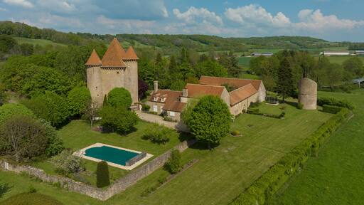 Aerial view of the Pancy castle in Angely Burgundy France with central keep protected by two circular towers, large outbuildings create a U-shaped wind around the courtyard standalone circular tower