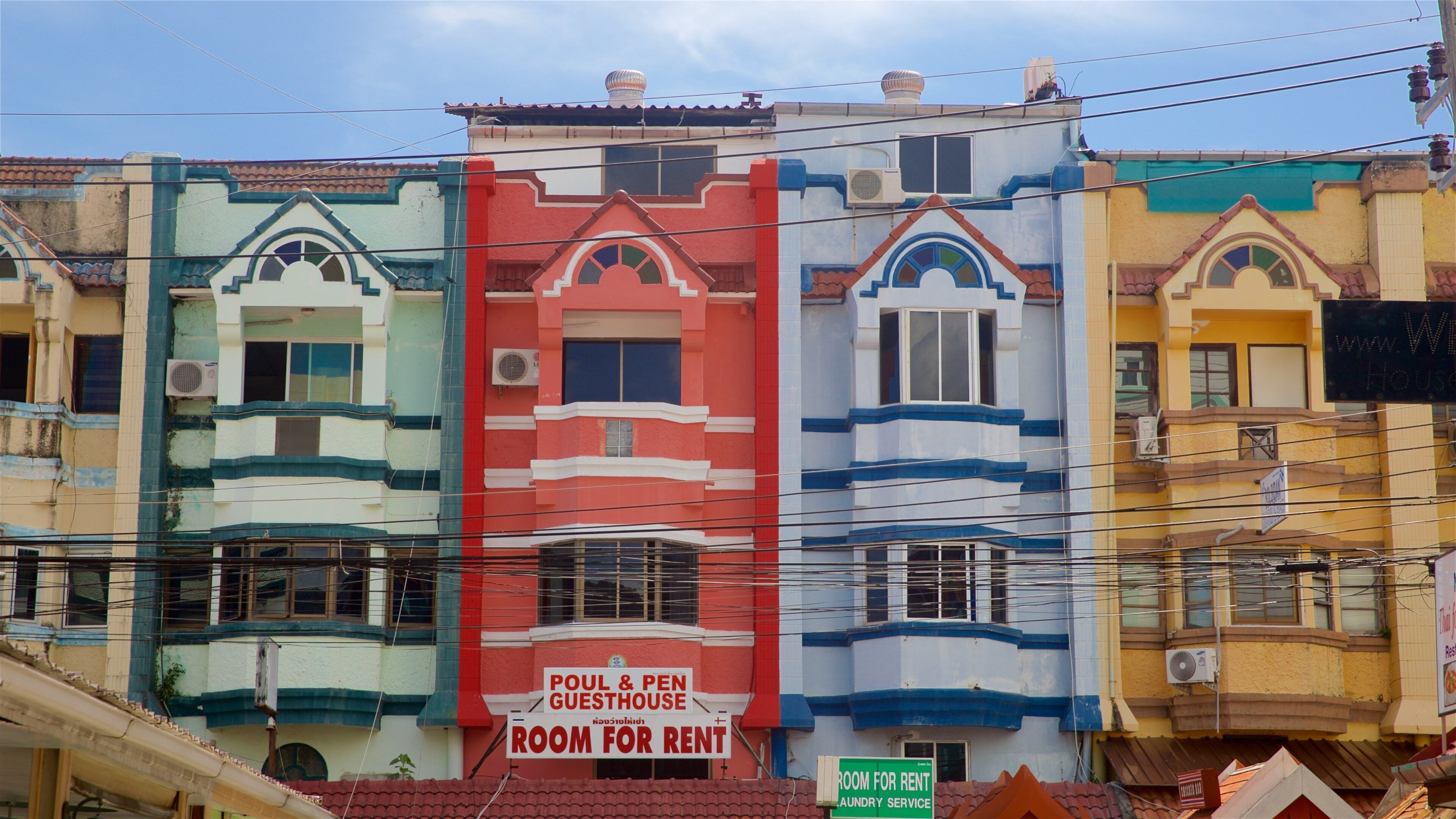A row of colorful buildings with a sign for a room for rent.