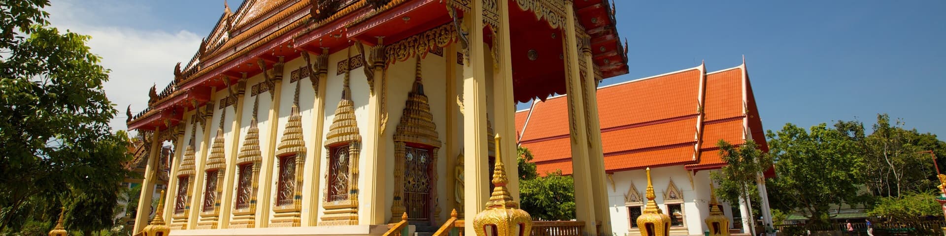 A traditional Thai temple with ornate golden decorations and a red roof.