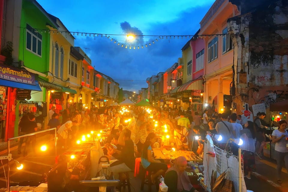 A bustling street market with colorful buildings and string lights.