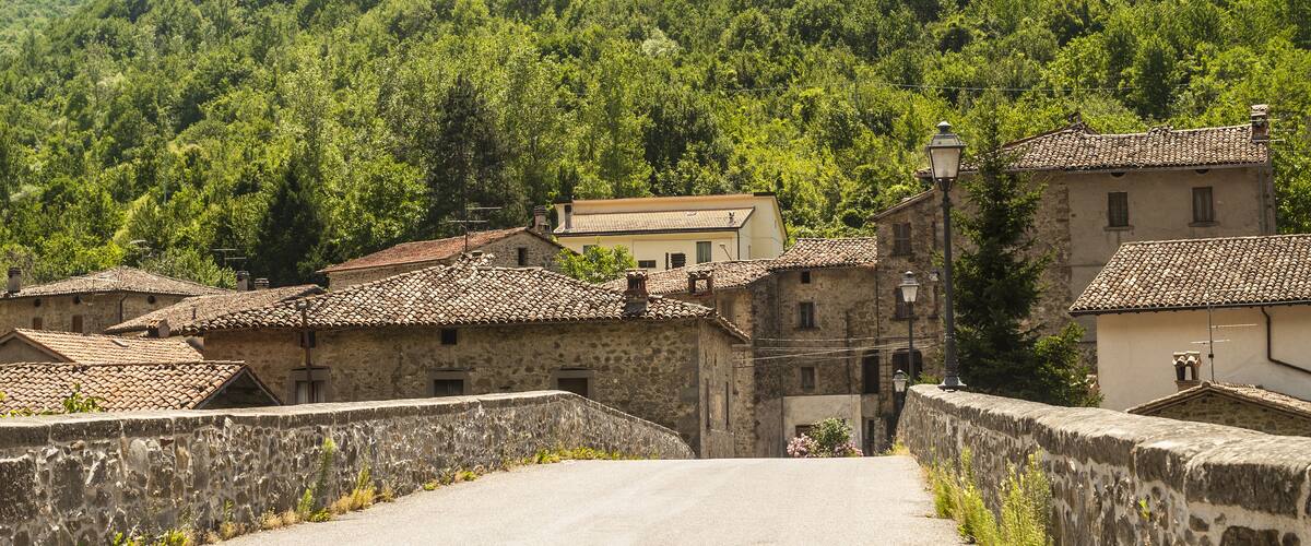 A village with stone buildings and a road leading up a hill.