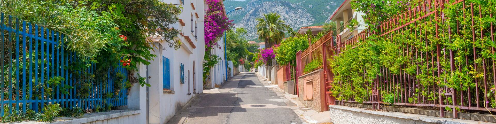 Harbor and houses of the town of Cala Gonone in Sardinia in sunlight in spring
