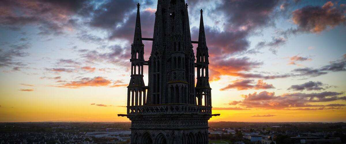 A Gothic cathedral with twin spires, set against a sunset sky.