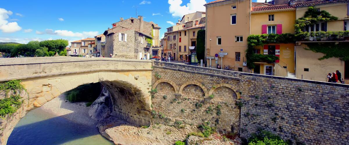 A stone bridge over a river, with buildings on either side.