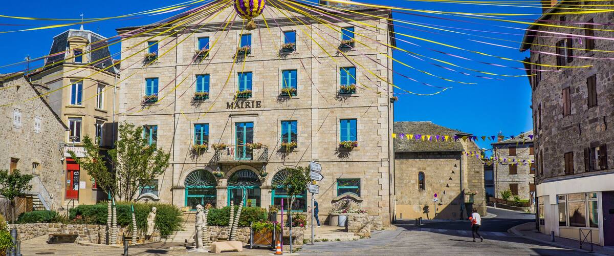 A historic building with a clock tower, surrounded by colorful ribbons and statues.