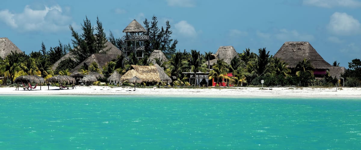 Huts, gazebos and hotels at a tropical beach, view from the water