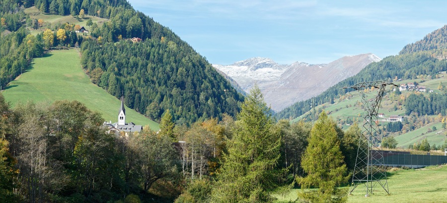 Panorama of the Alps mountains near the town of Rennweg am Katschberg with the power transmission line tower in the foreground. Carinthia, Austria.