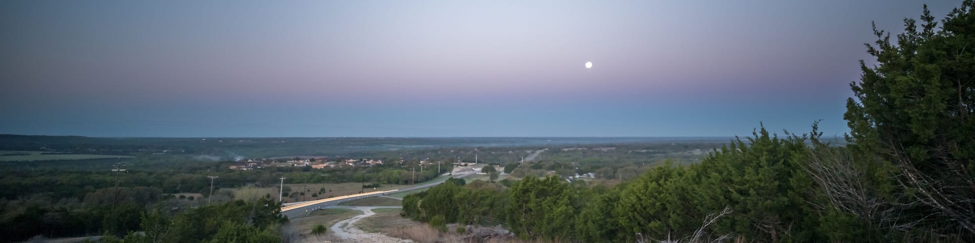 Wide Angle View of Full Moon Over Hill Country Valley During Early Morning Sunrise