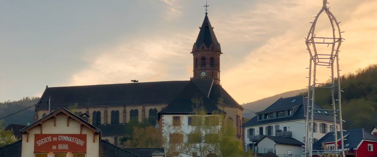 A church with a clock tower, a sign for a gymnasium, and a tall metal structure.