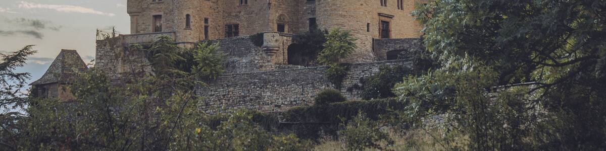 View of the ancient stone castle perched atop a hill, its towers piercing the sky against a backdrop of soft, twilight hues, Chateau de Cabrieres, Occitanie, France.