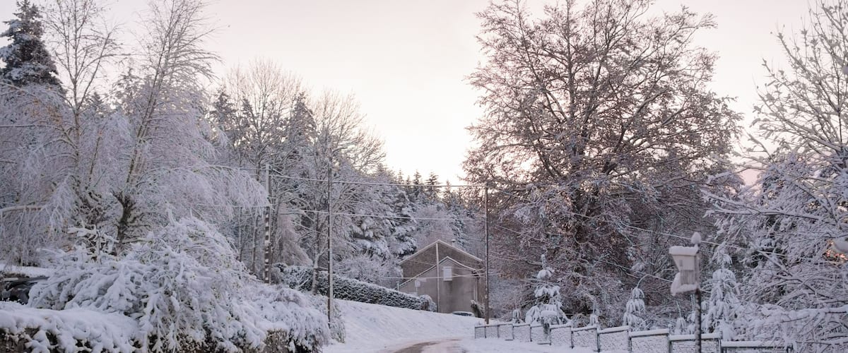 A snow-covered road with a house in the background.