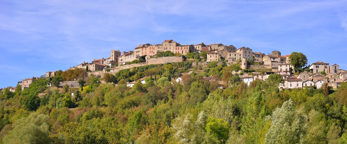 A hillside village with historic stone buildings and lush greenery.