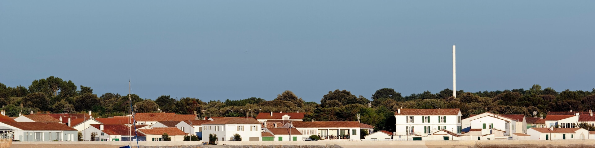 Une ville cĂŽtiĂšre avec des maisons, des bateaux et un phare.