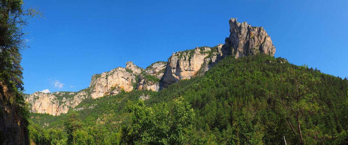 A rugged mountain with a prominent rocky peak and dense forested slopes.