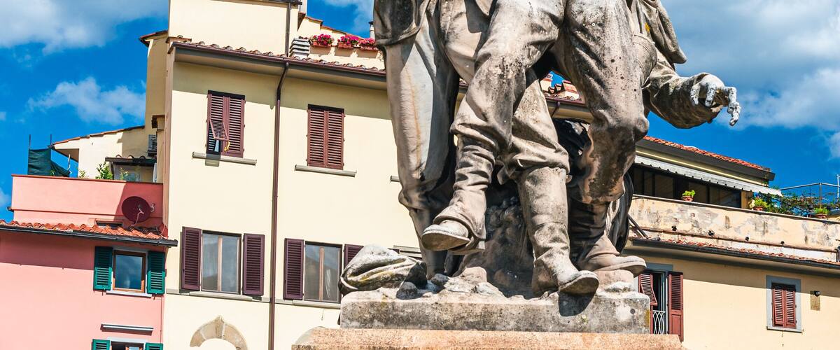 A statue of a man pointing with a sword, with a plaque reading "Al Forti Che Cadendo A Mentana Sacarono Roma Alla Libera Italia".