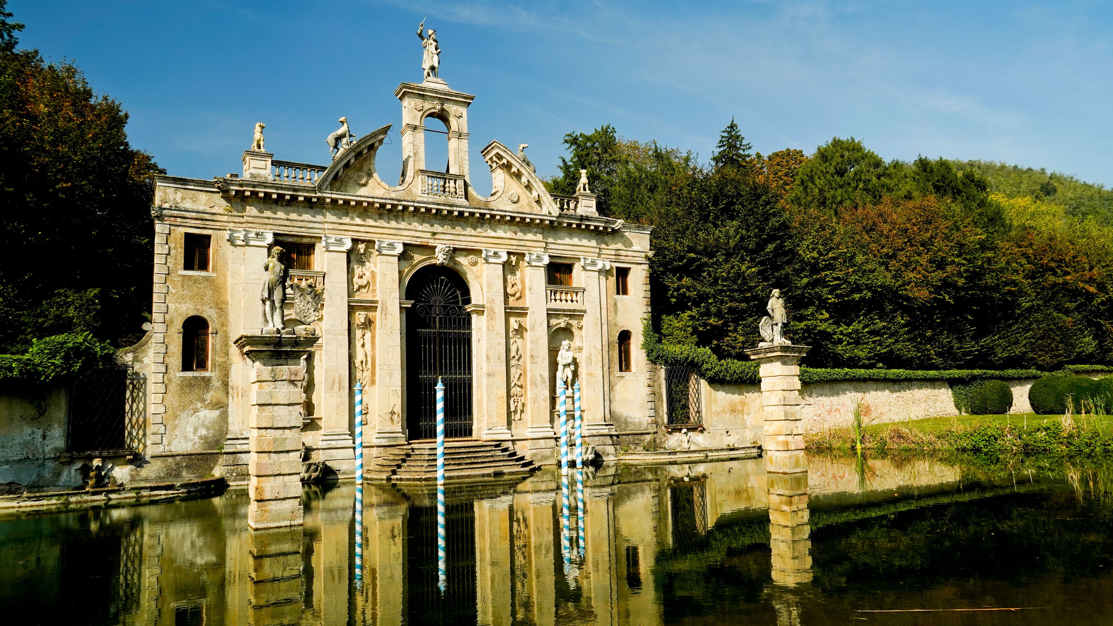 A historic building with statues and a fountain in front.