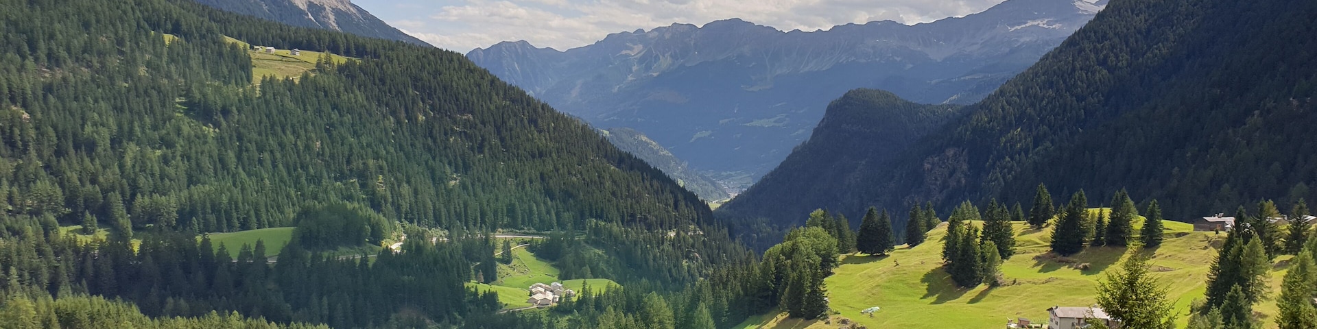 A mountainous landscape with dense forests, green valleys, and scattered houses.