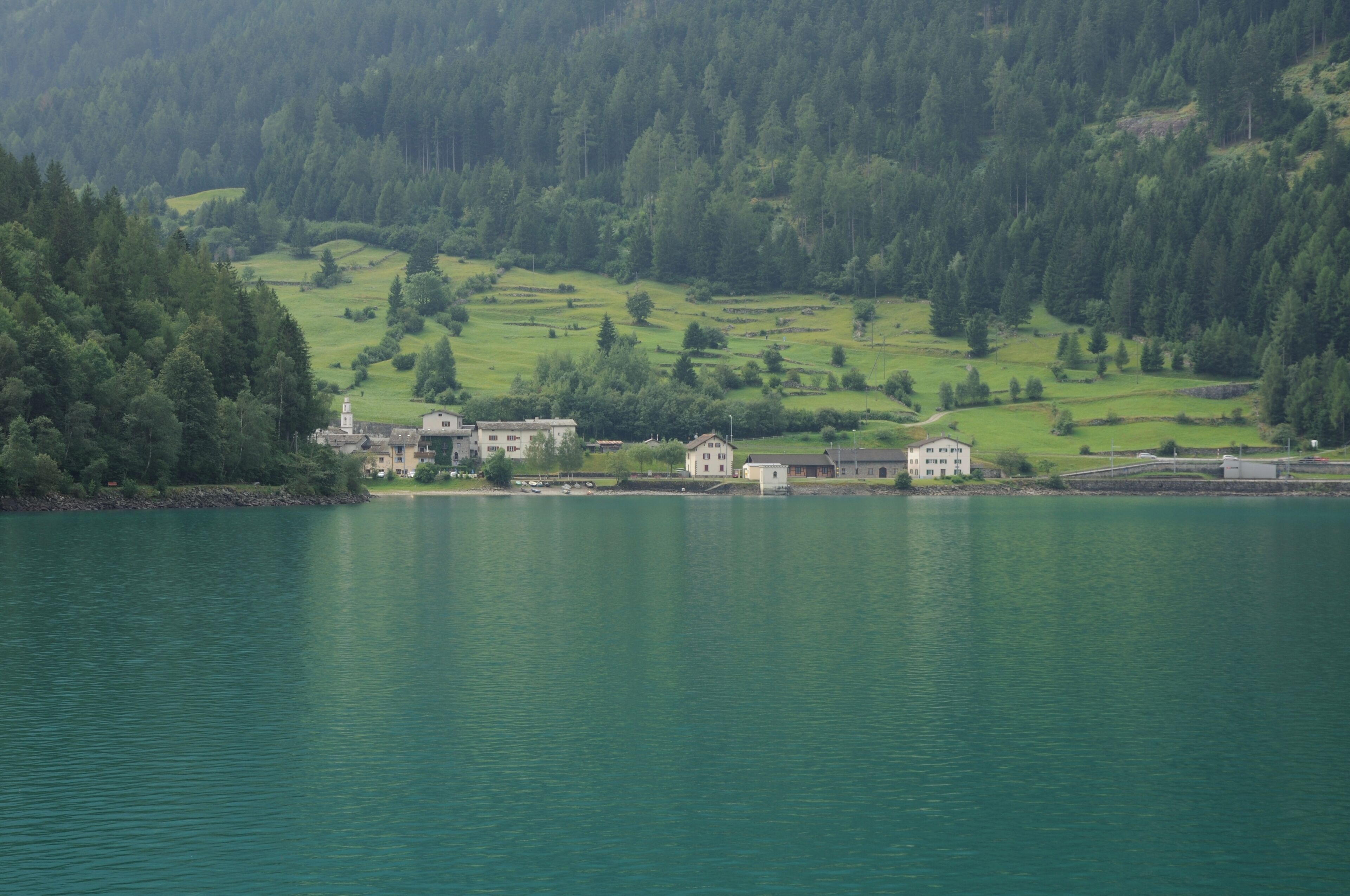 A lake surrounded by green hills and buildings.