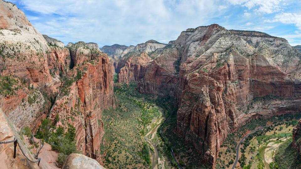 A canyon with red rock formations, a river, and a trail.