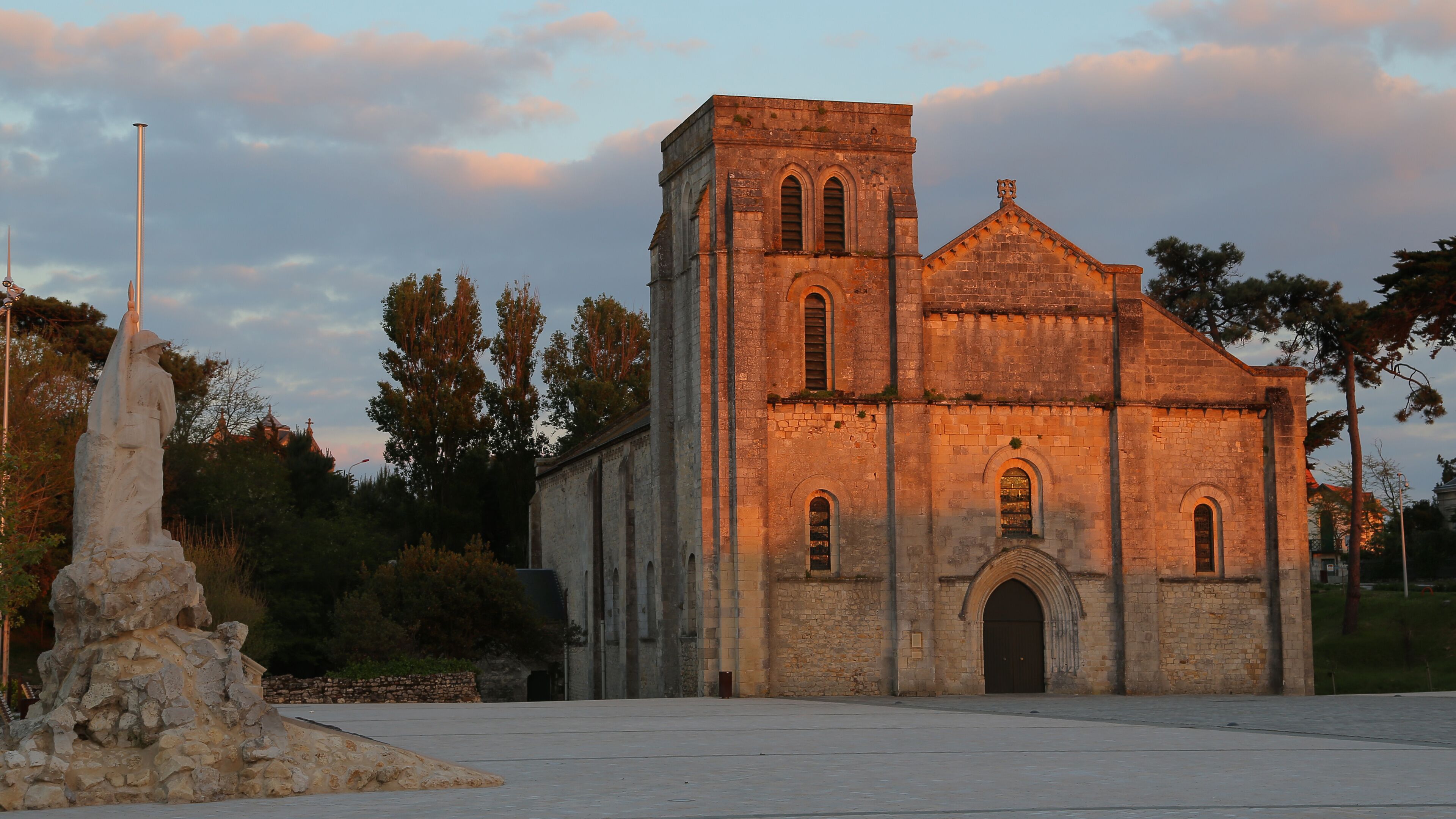 A historic church with a bell tower and a statue in front.