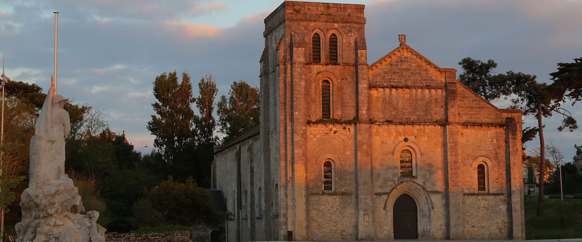 A historic church with a bell tower and a statue in front.