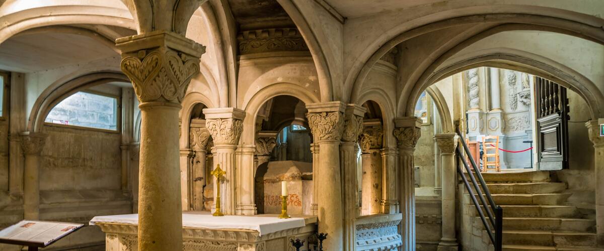 An interior with arched ceilings, stone columns, and a staircase.